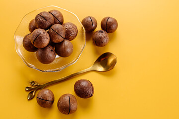 Dry macadamia nuts on a saucer on a yellow background