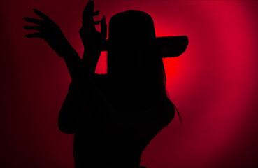 Dark red silhouette of a girl posing with her hands in the studio while looking seductive