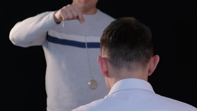 The hypnotist introduces the patient into a state of hypnosis with a pendulum
