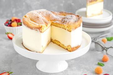Traditional Polish cake Karpatka on a gray concrete background. Cake of choux pastry dough and custard cream with fresh berries and powdered sugar on top. Carpathian cake. Copy space.