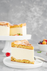 Traditional Polish cake Karpatka on a gray concrete background. Cake of choux pastry dough and custard cream with fresh berries and powdered sugar on top. Carpathian cake. Copy space.