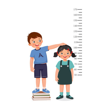 cute little boy standing on stack of books measuring height of little girl growth with measurement ruler on the background of wall