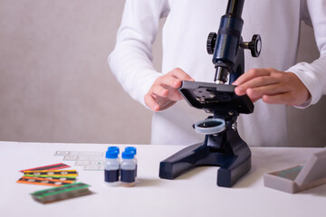 A schoolgirl with a microscope examines chemicals in test tubes, conducts experiments. The concept...