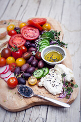 healthy snack of olives, tomatoes, olive oil, bread and cucumber