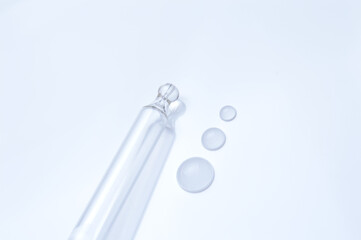 glass transparent jar and a cosmetic pipette with liquid droplets on a white background.