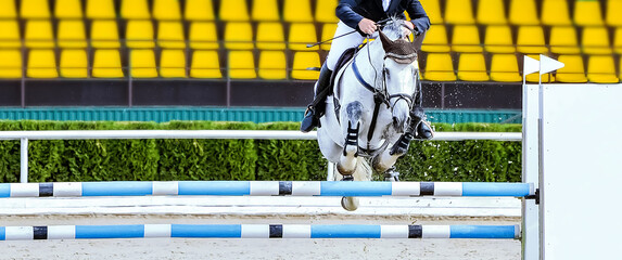 Horse and rider in uniform performing jump at Equestrian sport show jumping competition. Beautiful...