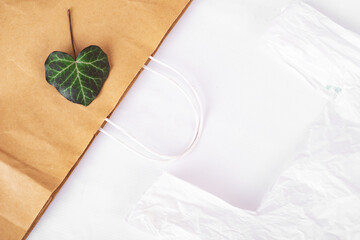 paper bag with green leaf and polyethylene bag on white back. using paper bags for purchases...