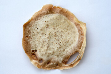 Thin ready pancake on a white plate top view. Thin burnt pancake. Dry fried pancake