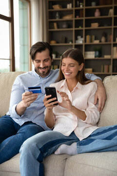 Vertical image young couple purchasing goods, make food delivery order, use card and smartphone, buy on internet enjoy services, ecommerce retail app usage. Secure payment, virtual e-services concept
