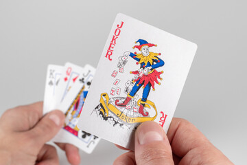 Jokerin hand on playing cards background