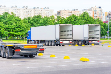 Trucks with open container trailers in the parking lot of the warehouse waiting to be loaded into...