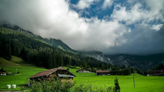 Time lapse of clouds moving around the mountains in a valley in the alps. Foggy summer day in a small village, Adelboden, Switzerlands.