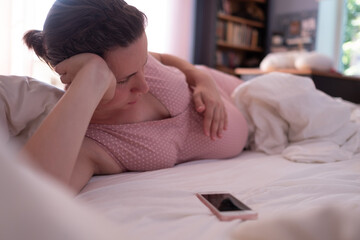 Caucasian woman with phone having labor contractions on sofa at home and breathing