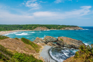 Picturesque bay with turquoise water and sandy beach, dense green forests and blue sky in the background. Silistar beach in sunny summer day, Bulgaria Black Sea coast.