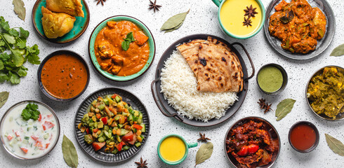 Indian ethnic food buffet on white concrete table from above: curry, samosa, rice biryani, dal, paneer, chapatti, naan, chicken tikka masala, mango lassi, dishes of India for dinner background - 480757522