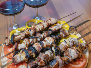 meat on skewers, pieces of fried pork, barbecue. Dish with vegetables and glasses with red wine