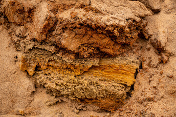 Textural sand, with  relief surface, multi-colored layers and different in size of granules, in outdoor sand career, after mining ore and sand for construction.
