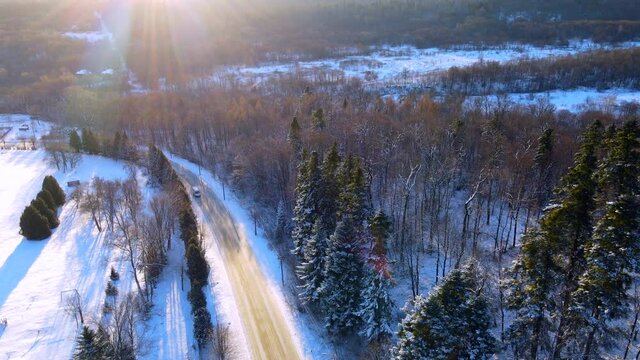 Video from a drone on the road leading through the frosty winter forests and groves covered with the first snow. High quality video