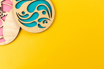 Handmade wooden easter eggs on a flat lay yellow background, top view photo, copy space