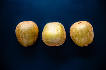 Three golden Kiwi (Actinidia) on dark high contrast background