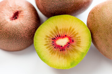 Red kiwi fruit berry half with three other kiwiw on white background