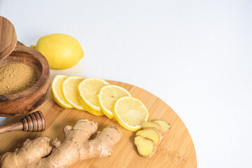 Fresh ginger root, lemon and honey on wooden round board, copyspase