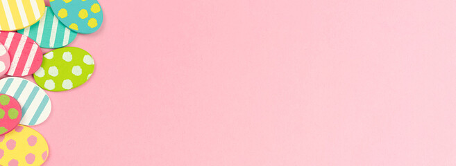 Obraz premium Colorful easter eggs banner on a bright pink background. Flat lay celebration greeting design, border concept, copy space and top view photo