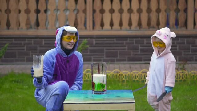 pour liquid into minzurka. wait chemical reaction. Watch as liquid rises and overflows out. Elephant toothpaste. Volcano with soda. Have fun family outdoor. Conduct experiments. two sisters laugh mix.