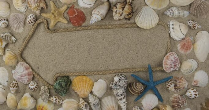 Arrow made of rope lying on the sand with space for design, space for text. Rotation of the pointer among shells and starfish