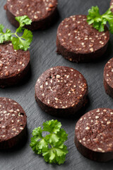 Raw Black Pudding with parsley on rustic stone board