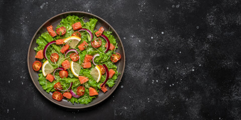 Salad with salmon and fresh vegetables on a black stone background. Top view, flat lay, copy space. Banner.