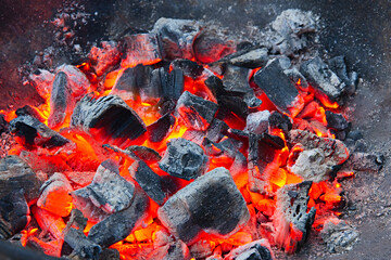 burning smoldering wood embers with red glow heat and gray ashes in a barbecue metal bowl