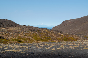 Snow capped mountain peak seen behind brown rocky hills