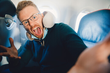 Obraz premium Concept of aerophobia, male tourist is afraid of flying on airplane