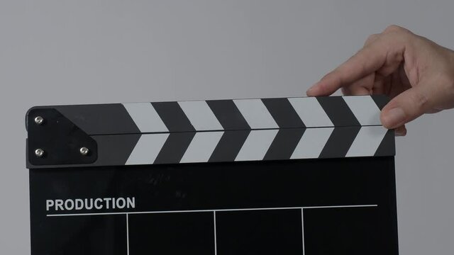Movie slate or clapperboard hitting. Close up hand holding empty film slate and clapping it. Open and close film slate for video production. film production. color background studio. ready to shoot
