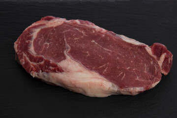 Raw marbled beef ribeye steak. Big plan. Black background. Top view.