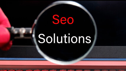 SEO SOLUTIONS the inscription found with a magnifying glass on a black laptop monitor. Concept photo