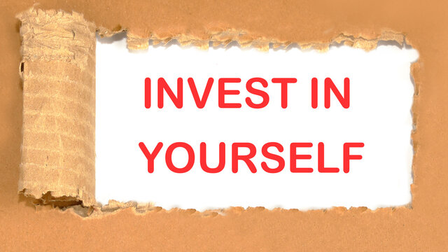 invest in yourself the inscription appearing behind the torn cardboard paper