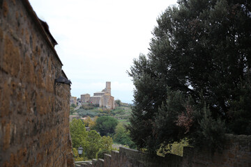 Fototapeta na wymiar Glimpse between the walls and distant view of the church of San Pietro, Tuscania, Tuscia, Lazio, Italy