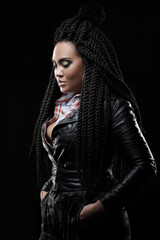 Girl in a leather jacket. Black background. Creative hairstyle, dreadlocks	
