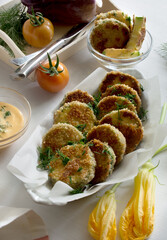 Breaded fried zucchini with tomatoes and sauce on white background. Vegetables on plate 