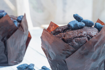 Chocolate sweet cakes muffins with berries on a white wooden table