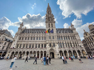 Obraz premium Gothic town hall building in Brussels, capital of Brussels and Europe, at the Grand Place with tourists and blue sky with white clouds