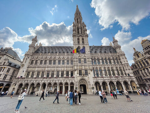 Gothic town hall building in Brussels, capital of Brussels and Europe, at the Grand Place with tourists and blue sky with white clouds