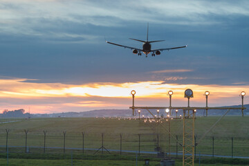 Fototapeta na wymiar Poland, Krakow, Balice Airport, Aircraft Landing against Sunset