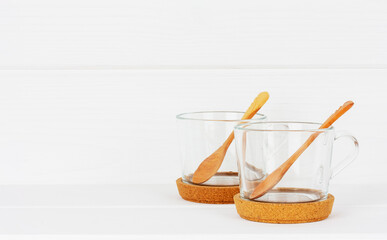 empty glass teacups with wooden spoons on cork stands on a white background with a copy space