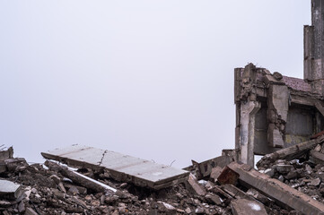 A pile of large concrete fragments against the background of the remains of the building and the...