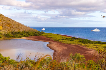 View of lagoon, red sand beach, and ocean from top of Rabida Island, Galapagos - Powered by Adobe