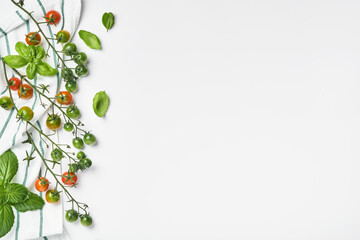 Fresh cherry tomato branches, basil leaves, napkin, pepper and pepper mill on a white background. Food cooking background and mock up.