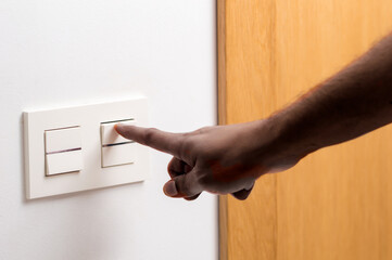 Close up of man hand turning on the light with a wall switch at home